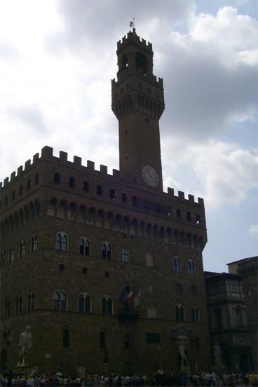 The bell tower of the Palazzo Vecchio with the statues in the Piazza Della Signoria visible below.