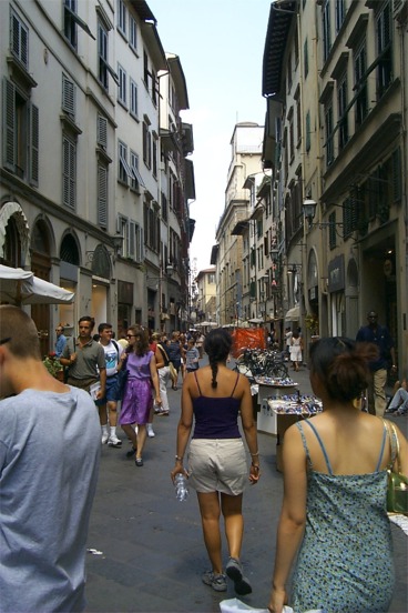 Rachel walking down a street with shops.  Really the story of Florence is the numerous shops that line it's streets as well as roaming merchants trying to sell their goods.  I plan on returning when the good fortune of gainful employment allows for the procurement of the fine Florence wears. (Grad-student salaries don't provide the means)