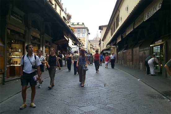 The Ponte Vecchio (Old Bridge).  There have been stores on the Ponte Vecchio since the 13th century: initially of all types, butchers, fishmongers, tanners, whose waste caused quite a stench.  In 1593 Ferdinand I decreed that only goldsmiths and jewelers be allowed to have stores on the bridge.  This shot was taken toward the end of the day when the stores were closing - they lowered wooden doors over the store fronts at night.